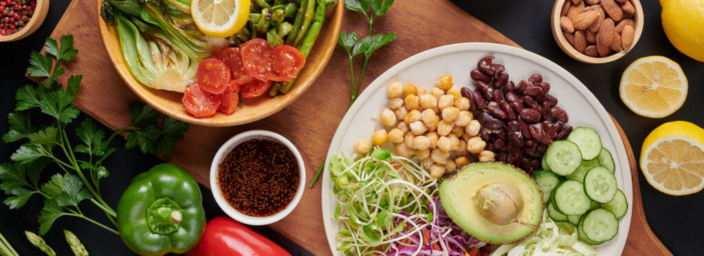 Mesa con dos platos llenos de vegetales, legumbres y granos. Toma desde arriba